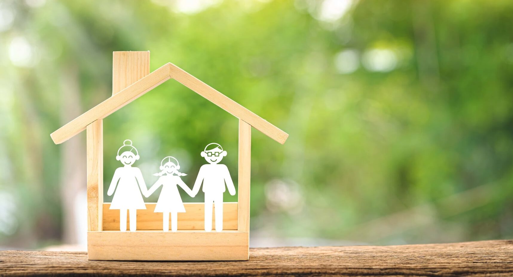 Wooden home with happy family of paper art is placed inside on nature bokeh in the public park The saving money for house or real estate owner in the future concept e1744057701221
