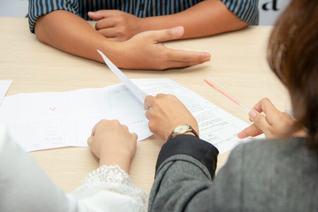 man sitting across from people with documents